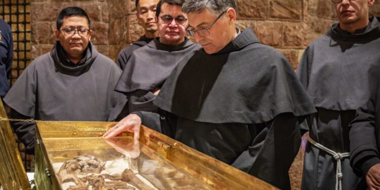 Why do the bones of St. Francis draw hundreds of thousands of pilgrims?