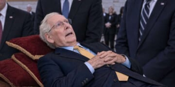 Mitch McConnell lying on a bed in the U.S. Capitol Rotunda.